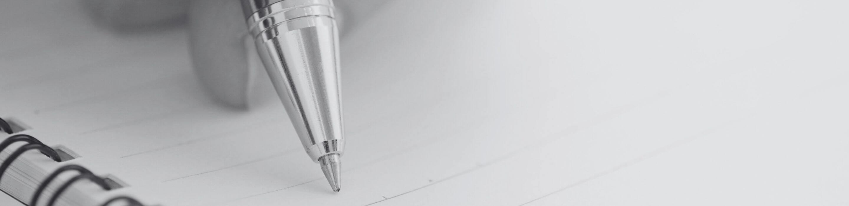 Close-up of a hand holding a pen poised above an open notebook, capturing a quiet moment of intention.