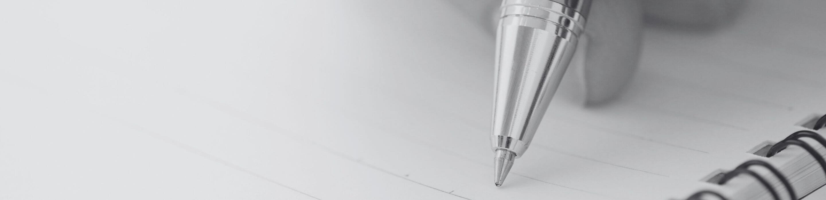 Close-up of a hand holding a pen poised above an open notebook, capturing a quiet moment of intention.